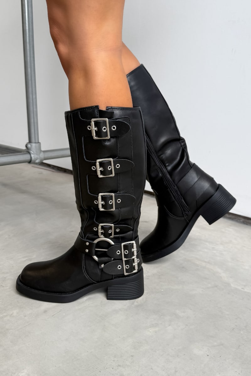 Black knee-high boots with multiple buckles on a light gray floor. GEORGIA Chunky Buckle Biker Boots - Black.