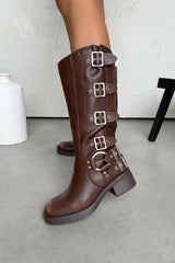Brown knee-high boots with buckles on a light gray floor.