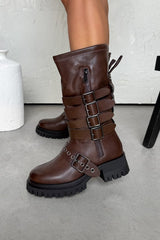 Brown leather boots with buckles on a light gray floor.