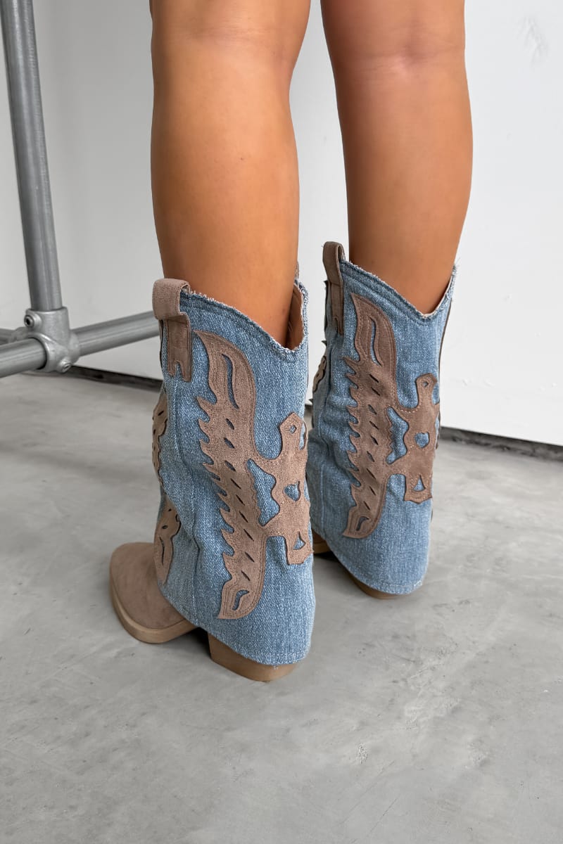 Denim cowboy boots with brown details worn by a person on a light gray floor. ADA Flared Cowboy Western Boots - Denim/Beige.
