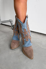 Brown cowboy boots with decorative cut-out design on a concrete floor.