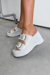 White platform sandals with frayed edges worn by a person on a concrete floor. DEMI Woven Buckle Wedge Sandals - Beige - 2