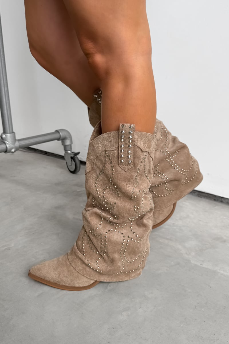 Beige suede Western cowboy boots worn by a person on a light gray floor. ETTA Studded Slouched Cowboy Western Boots - Beige Suede - 3