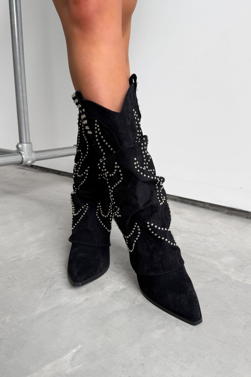 Black western cowboy studded boots worn by a person on a concrete floor. ETTA Studded Slouched Cowboy Western Boots - Black Suede - 2