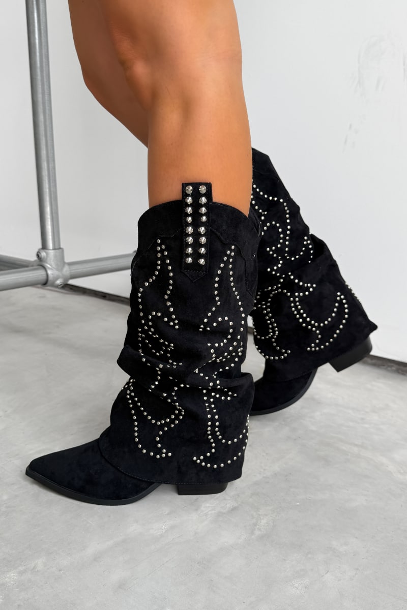 Black western cowboy studded boots worn by a person on a concrete floor. ETTA Studded Slouched Cowboy Western Boots - Black Suede - 1