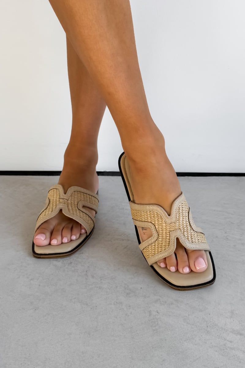 Beige sandals with woven design worn by a person on a light gray background