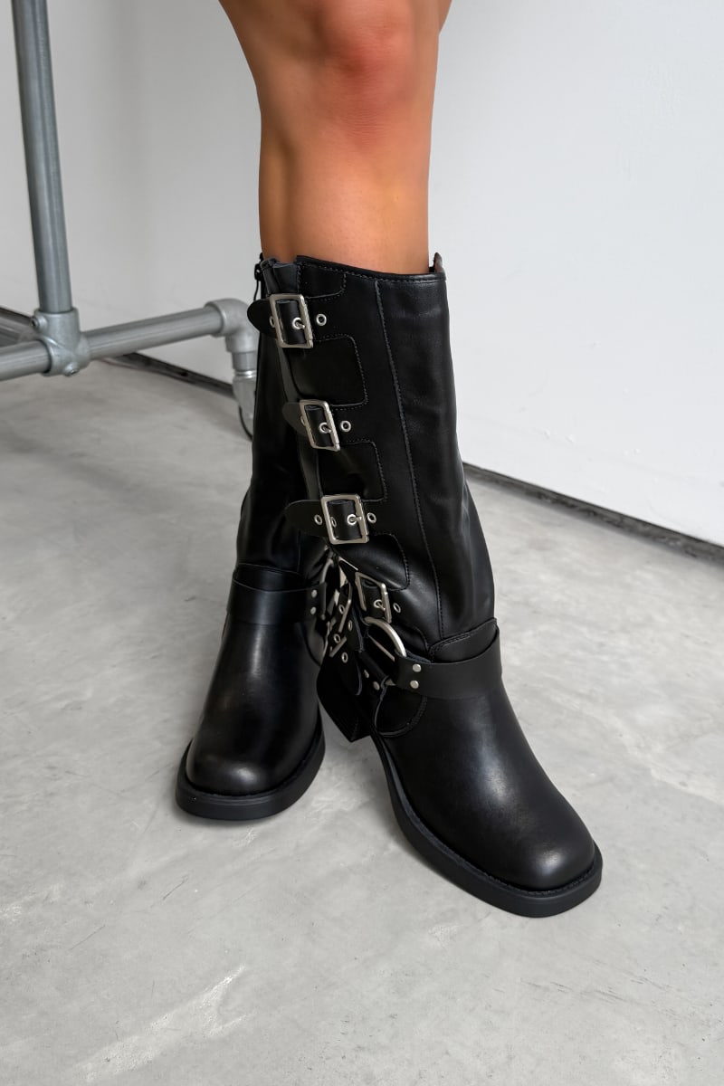 Black knee-high boots with multiple buckles on a light gray floor. GEORGIA Chunky Buckle Biker Boots - Black - 2