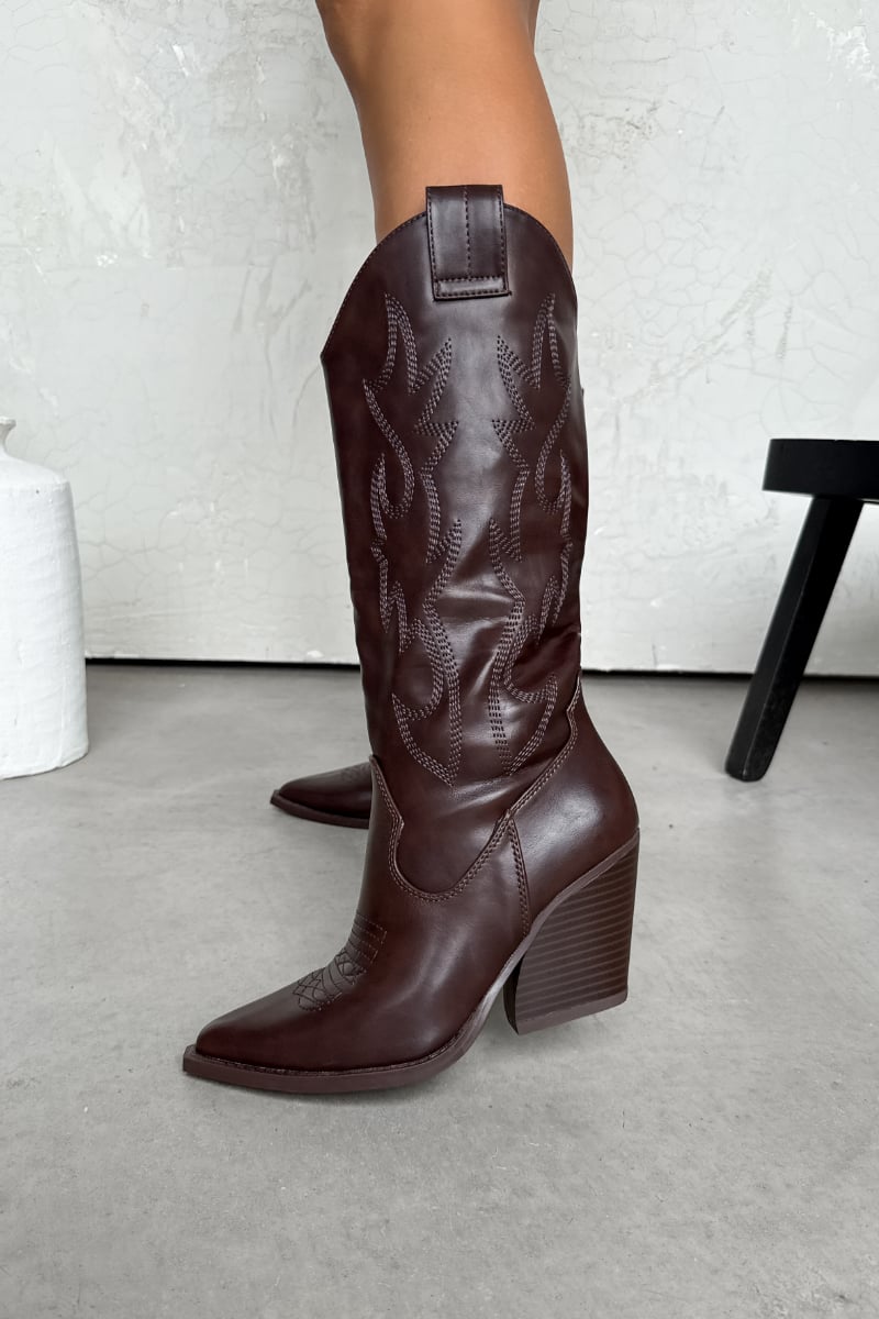 Brown cowboy boots on a light gray floor with a white wall background