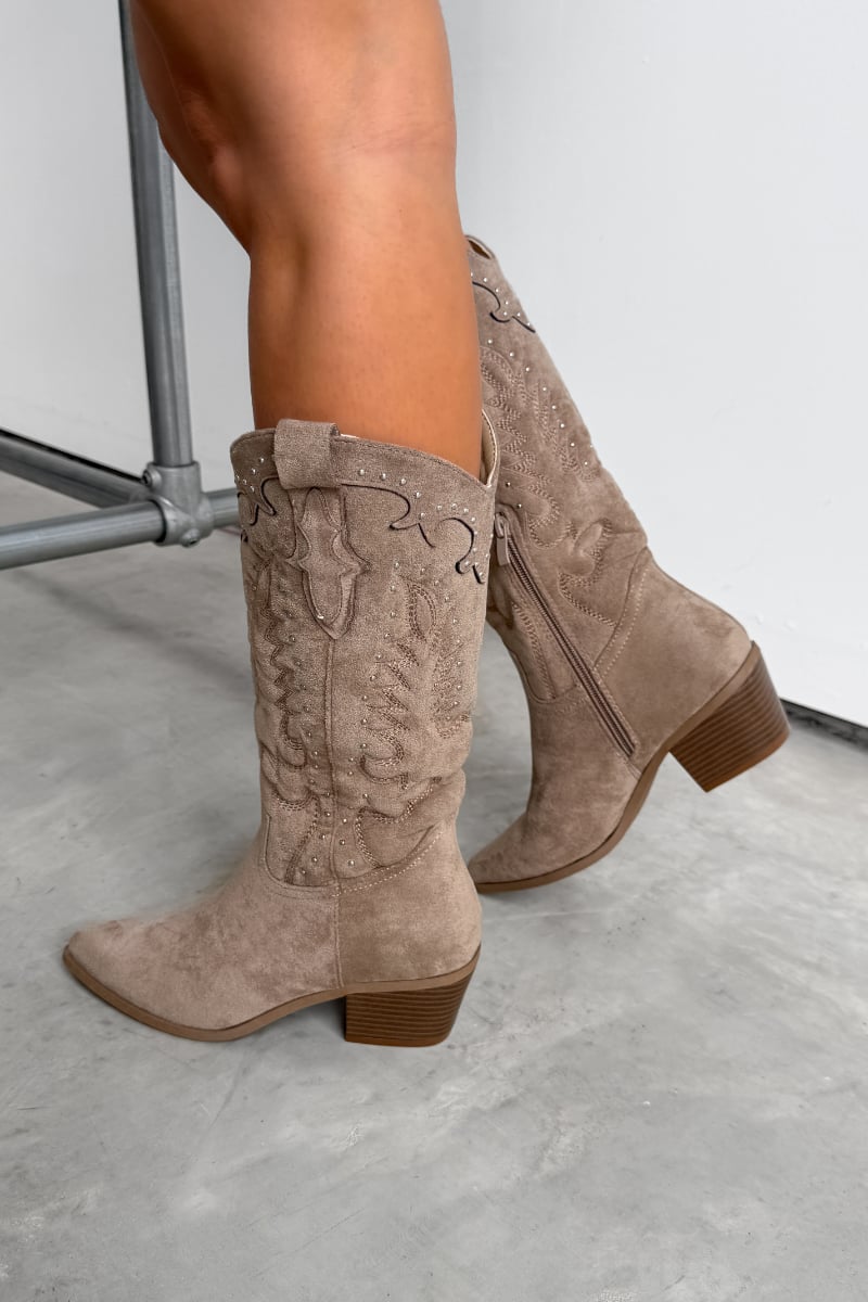 Beige suede cowboy boots worn by a person on a light gray floor. KANSAS Knee High Western Cowboy Boots - Taupe.