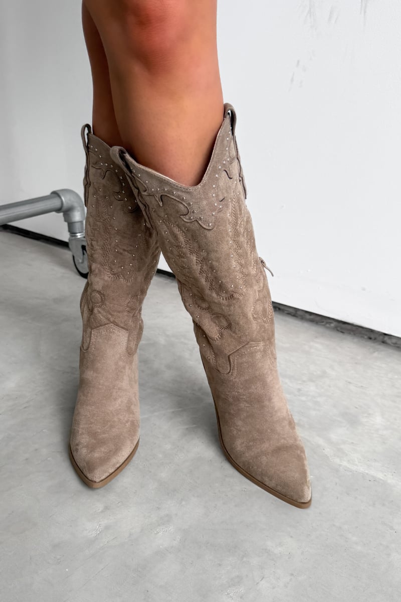 Beige suede knee-high boots worn by a person on a light gray floor. KANSAS Knee High Western Cowboy Boots - Taupe - 1.