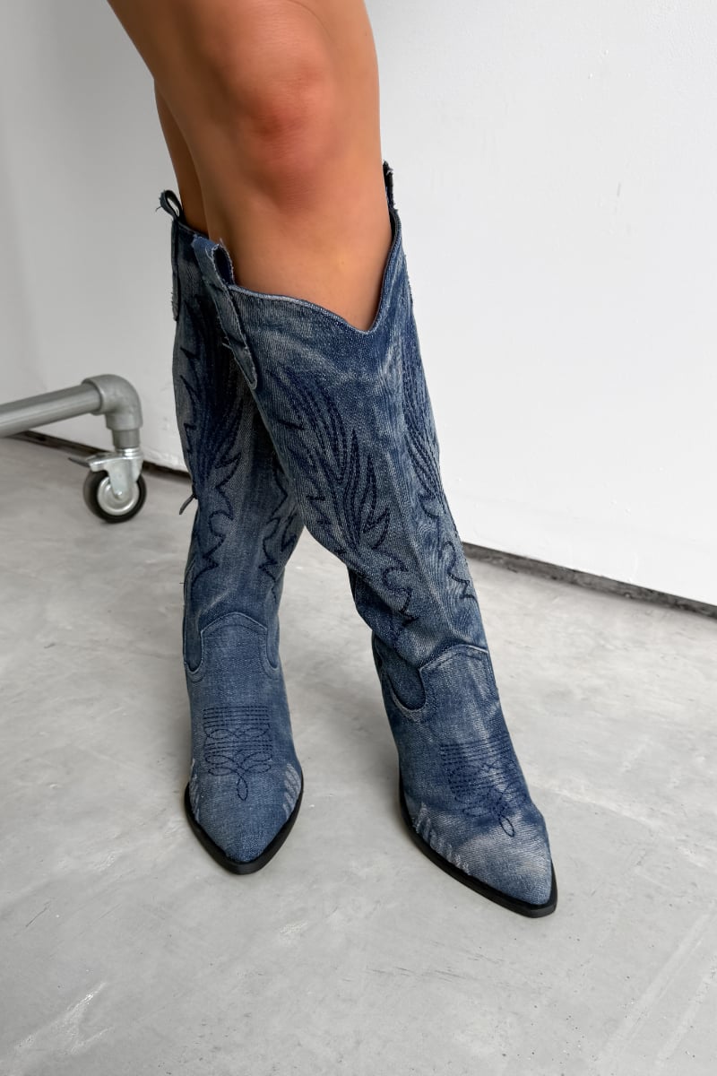 Blue cowboy boots worn by a person on a white background. TENNESSEE Knee High Cowboy Western Boots - Dark Denim